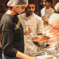 One of our chefs guides a guest as she spreads the San Marzano tomato sauce on her dough. We're there to help you make the perfect pie.