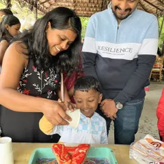 This is what pure family fun looks like. A mother and father help their son create his first fluid art masterpiece during a birthday party, full of smiles and colorful messes.