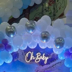 A modern "Oh Baby" shower theme with a cool blue and purple color palette. The decor features a neon sign, a textured backdrop, and silver accent balloons for a chic celebration.