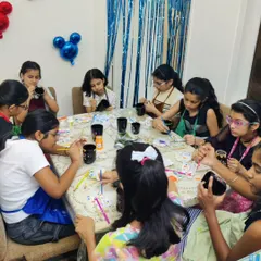A candid shot of the kids deeply focused on their dot mandala mug painting during Amaira's birthday celebration.