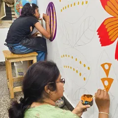 My student and I work together on a large-scale floral mural for our sensory classroom, inspired by the whimsical art of Mary Blair.