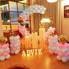 A colorful Cocomelon themed first birthday party. This setup features character foil balloons, a pastel balloon arch, a small white picket fence, and light-up letters for the child's name, creating a playful atmosphere.