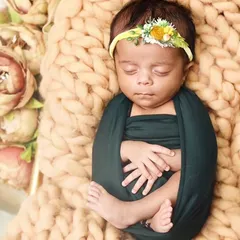 Safely swaddled and sleeping soundly on a chunky knit blanket in a miniature golden cot. This classic pose highlights the delicate features of a newborn.