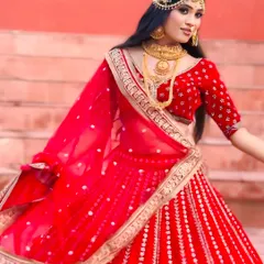 A vibrant red bridal lehenga with intricate silver and gold embroidery. The model's twirl showcases the beautiful flare of the skirt, making it a perfect choice for a bride who wants to feel like royalty.