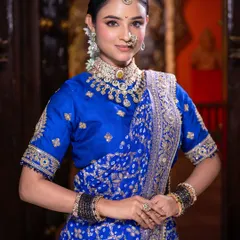 A portrait of poise and tradition. The soft lighting highlights the flawless skin work and the intricate details of her choker and nath.
