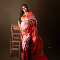 A classic portrait of a mom-to-be in a beautiful pink and red silk saree, accessorized with traditional gold jewelry.
