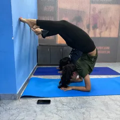Another student exploring a forearm stand variation against the wall. We use props and the wall to safely build strength and confidence in inversions.