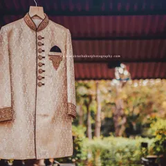 Another angle of the groom's elegant cream sherwani, highlighting the rich fabric and classic design against a natural backdrop.