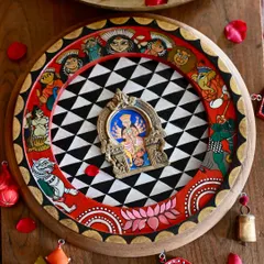 A hand-painted homage to the goddess Durga, housed within a restored vintage clock frame and a salvaged brass Prabhavali. This piece is inspired by the protective spirit of a dreamcatcher and the narrative style of Pattachitra art, adorned with found-object trims to complete its story.