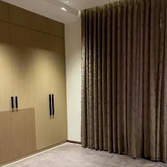 A floor-to-ceiling wardrobe designed with a two-tone finish. The upper cabinets in a solid matte laminate contrast with the lower wood-grain texture, creating a clean, modern look with minimalist black handles.