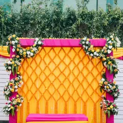 This bright and colorful backdrop was designed for a bridal Haldi ceremony. We used a combination of a yellow marigold lattice, a pink frame, and fresh flower bouquets to create a festive and cheerful photo corner.