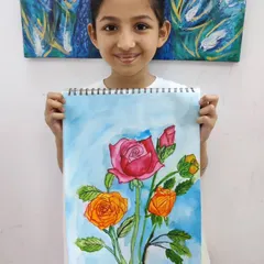 A young artist holds up her beautiful watercolor painting of roses, demonstrating her skill in color blending and creating delicate floral forms.