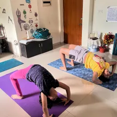 Two young clients work on backbends, one in a full wheel pose and the other in a bridge. I provide variations to suit different levels of flexibility and strength.