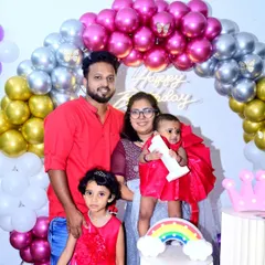Getting a great family portrait is a key part of any celebration. Here, the family poses together during their daughter's first birthday, with the themed balloon arch creating a perfect backdrop for a sharp, well-lit family photograph.