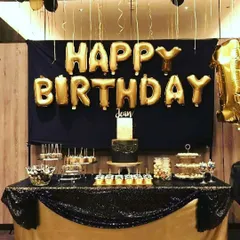 This birthday decoration in black and gold includes a backdrop and a decorated table, creating a perfect spot for the cake and desserts.