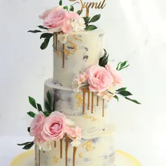 For a touch of rustic elegance, this semi-naked cake is a beautiful choice. The lightly frosted layers are adorned with a gold drip and clusters of delicate pink sugar flowers, perfect for a chic and romantic wedding.