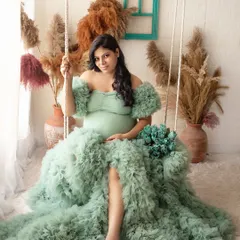 A full-length portrait featuring a mint green ruffled gown. The studio swing and boho-chic pampas grass decor add a touch of whimsy to this elegant shot.