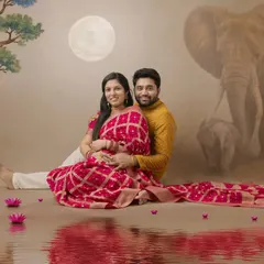 A dreamy, traditional maternity portrait. The painted backdrop featuring elephants and a full moon adds a touch of Indian folklore and magic to the scene.
