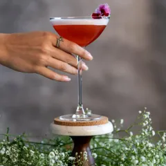A festive holiday cocktail I call 'Santa’s Indulgence'. It's a mix of gin, house-made strawberry liqueur, rhubarb, and fresh lime, garnished with edible flowers.
