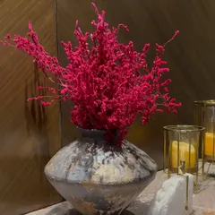 A pop of vibrant pink against a rustic vase. This is a detail from a larger luxury decor setup, showing our love for bold colors and interesting textures.