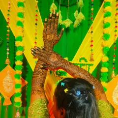 A creative pose by a bride showing off her full mehandi. The green and yellow decor of the mehandi function looks so vibrant.