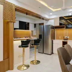 An open kitchen concept featuring a breakfast counter that separates it from the dining area. The design includes a CNC-cut jali panel, adding a decorative touch.