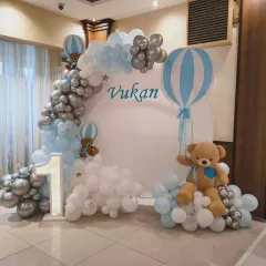 A "We're on cloud nine" theme for Vukan's celebration. I used white, blue, and silver balloons to create clouds around a circular backdrop with hot air balloon accents.