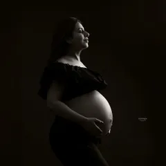 A serene and powerful bare-bump portrait using low-key lighting. This technique creates deep shadows and soft highlights, resulting in a dramatic and artistic black and white photograph.