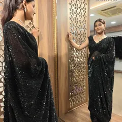 The mirror shot shows how this black saree drapes beautifully, creating a flattering silhouette.