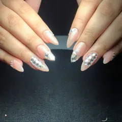 An elegant and luxurious design featuring a nude base on stiletto nails. The look is enhanced with silver mirrored crystals arranged in a sophisticated pattern on accent nails.