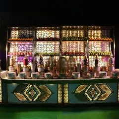 A grand and opulent beverage station. The intricately designed, backlit counter and shelving create a spectacular display for a wide array of drinks, making it a definite highlight of the event.