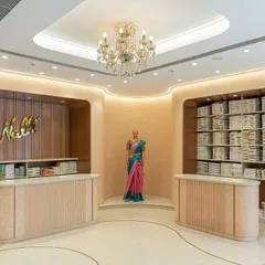 The entrance lobby of the Nalli store, designed as a hybrid retail and visual merchandising space. The curved counters and soft lighting create an elegant and welcoming first impression.
