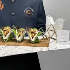 Our Crispy Chicken Bao is a crowd-pleaser. Soft steamed buns are filled with crispy chicken and fresh greens, served in a modern, geometric stand that adds a touch of style to your appetizer selection.