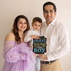 A joyful family announcement! This family of three is excited to become four, and the sign they hold adds a fun, personal touch to their maternity shoot.