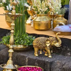 The essence of South Indian wedding decor. This arrangement features traditional brass elements like a 'diya' (lamp) and an elephant statue, softened by fresh tuberose and lotus petals.