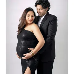 A classic and loving pose of a couple during their studio maternity session. Dressed in elegant black, they share a tender moment looking down at the baby bump.