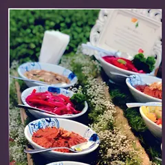 A close-up of our vibrant appetizer selection, including pickled onions and savory dips, presented in elegant patterned bowls and surrounded by fresh baby's breath.
