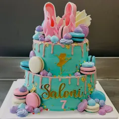 A vibrant two-tier ballerina cake for Saloni's 7th birthday, adorned with macarons, meringues, and a beautiful drip effect.