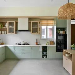 This kitchen from our 'House of Kismish' project exudes a European cottage vibe with its sage green cabinetry and delicate piccolo tiles. The design includes open shelving and a dedicated breakfast nook.