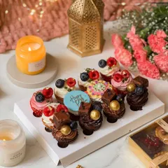 A box of twelve assorted mini cupcakes, beautifully decorated with fresh berries, chocolate, and a "Happy Rakhi" plaque. These bite-sized delights are perfect for sharing and celebrating together.