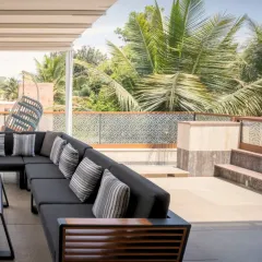 Reimagining the outdoor experience. This covered terrace features a sleek, modern sofa that overlooks a lush canopy of palm trees, blurring the line between a private residence and a tropical resort.
