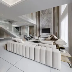 A double-height living room that exudes grandeur. We used a floor-to-ceiling marble feature wall for the TV and a statement channel-tufted sofa to anchor this breathtaking space.