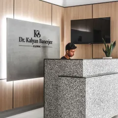 A closer view of the reception at Dr. Banerjee's Clinic. The custom-designed desk, made from black and white quartz, serves as an elegant centerpiece, while the backlit signage and wood paneling establish a professional and welcoming atmosphere.