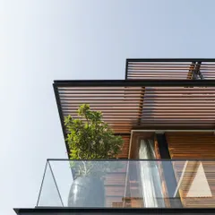A detail of the layered pergolas and glass balcony at Villa re:FORM, showcasing the clean lines and modern aesthetic of the renovation.