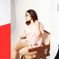 Posing and props are essential for showing apparel in a natural way. Here, the model's relaxed pose on a modern chair helps display the fit and drape of the oversized pink t-shirt, providing a lifestyle context that is perfect for product pages.
