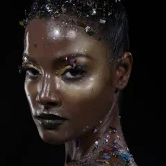 A direct and intense portrait from my 'glass skin' series. This look features a high-shine, almost wet-look skin finish, a black glitter lip, and fragments of confetti on the skin and hair for a dramatic, textured effect.