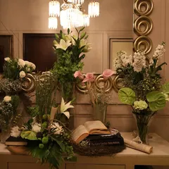 A stunning vintage-inspired console table arrangement. We combined various bouquets of white lilies, roses, and anthuriums with antique books and scrolls to create a display that tells a story.