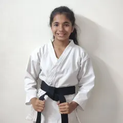 Lekissha proudly wearing her new black belt. This belt is not just a piece of cloth; it is a symbol of her hard work and the beginning of a new chapter in her martial arts journey.