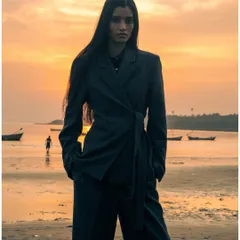 A powerful, full-length portrait during golden hour. The model's direct gaze and strong stance contrast with the soft, warm light, creating a captivating fashion editorial image.