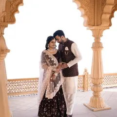 A romantic portrait of the couple. The bride's makeup is soft and elegant, with a focus on flawless skin, perfect for her deep wine colored lehenga and the architectural backdrop.